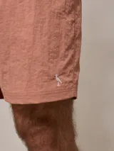 Short de baño azul marino con cintura elástica ajustable con cordón y logo de la marca bordado en rojo en la pierna izquierda.