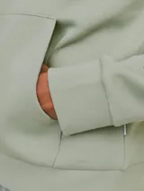 Canguro verde claro con capucha y cordones ajustables. Tiene un bolsillo tipo canguro en la parte delantera y el logo de Jack & Jones estampado en blanco en el pecho.