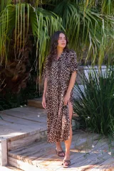 Vestido camisero de muselina color negro, de largo midi, con cuello clásico, manga corta y cierre frontal con botones.