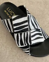 Sandalias bajas de cuero negro con tiras anchas cruzadas y plantilla anatómica color camel.