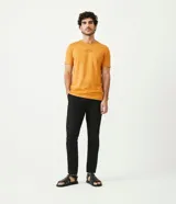 Remera color mostaza de corte slim fit, cuello redondo y manga corta. Presenta un estampado tipográfico en el pecho.