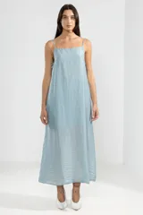 Vestido largo hasta el tobillo color celeste, en tejido arrugado liviano, con escote recto y finos breteles. Detalles de lazos en los costados, forro hasta arriba de las rodillas y caída posterior más larga.