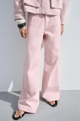 Pantalón de jean color rosa, de tiro alto, corte recto y largo hasta el tobillo. Presenta bolsillos de parche delanteros y traseros, trabillas en la cintura y cierre frontal con cremallera y botón.