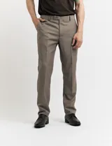 Traje de vestir color marrón topo, compuesto por saco de dos botones con solapa de muesca, dos bolsillos delanteros con solapa y un bolsillo superior. Pantalón de vestir con corte recto y bolsillos laterales. Incluye camisa blanca y corbata azul con lunares blancos.