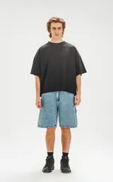 Bermuda de denim celeste con calce oversize, estilo carpintero y proceso de efecto desgaste.