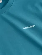 Remera azul petróleo de algodón, con cuello redondo y logo de Calvin Klein bordado en blanco en el pecho.