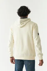 Canguro color crema con capucha y cordones negros, estampado frontal con la imagen de la creación de Adán y la palabra "Renaissance". Tiene bolsillos laterales y logo en grifa de goma.