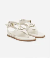 Sandalia plana de cuero sintético color blanco, con tiras superpuestas, detalle de aro metálico y cierre ajustable con hebilla.