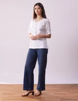 Blusa blanca de algodón con escote en V, abertura con botones y mangas cortas con detalle de broderie.