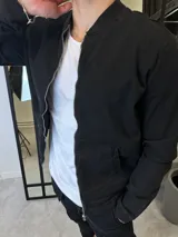 Campera bomber negra de gabardina con cierre frontal y bolsillos laterales.