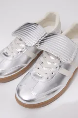 Zapatillas plateadas con detalles en blanco y suela de goma color caramelo.