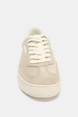 Zapatillas deportivas color beige, con cuerpo en combinación de materiales y cierre mediante cordones. La altura de la suela es de 3 cm.