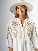 Vestido corto blanco de algodón italiano con bordado azul, mangas tres cuartos y botones frontales.