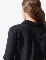 Camisa blanca de manga larga con cuello con solapa y abertura central con botones. Delantera con bolsillos aplicados.