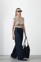 Top sin mangas color beige, confeccionado en tejido acanalado. Presenta hombreras definidas y un recorte fruncido bajo el busto que ajusta la silueta.