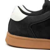 Zapatillas urbanas negras de cuero sintético con suela marrón y cordones blancos.