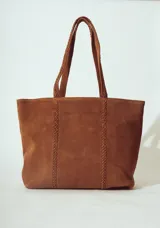 Bolso tipo tote bag de gamuza color marrón, con asas trenzadas y paneles laterales con detalle de trenzado vertical.