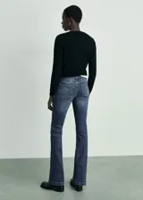 Pantalón de jean azul oscuro, tiro bajo, corte flare y cinco bolsillos.