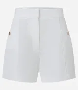 Short blanco de sastrería con cintura alta, bolsillos laterales con tachuelas metalizadas, recortes delanteros con costura aparente, bolsillos falsos y pinzas traseras.