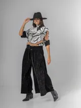 Pantalón ancho de corderoy negro con pliegues marcados en la parte delantera y cintura elástica. Incluye un cinturón negro con hebilla cuadrada.