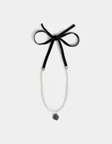Collar corto de perlas sintéticas con dije de rosa metálica plateada y cierre de cinta de terciopelo negro.