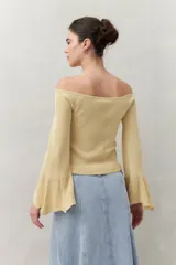 Top tejido color beige con escote off-shoulder y mangas largas acampanadas.