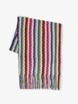 Poncho de punto multicolor con diseño de rayas verticales en zigzag y flecos en el borde inferior.