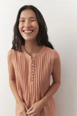 Vestido corto celeste de lino, sin mangas, con cuello mao, detalle de plisados y botones a tono.