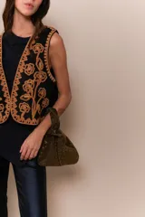 Chaleco negro con bordado en dorado, sin mangas y corte marcado sobre la cintura.