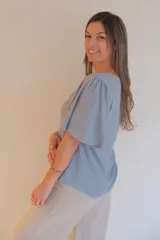 Blusa celeste de tela tipo jean, con escote en V y mangas cortas con volados.