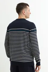 Sweater de punto a rayas horizontales blancas sobre fondo azul marino, con una línea horizontal verde en la parte superior. Cuello redondo, puños y bajo acanalados.