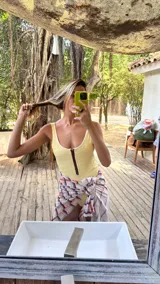 Traje de baño enterizo amarillo con textura arrugada, breteles finos y cierre marrón en el frente.