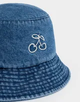 Piluso de denim azul con bordado de cerezas blancas en el frente.