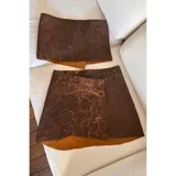Minifalda marrón de cuero ovino con textura veteada y cierre con broches metálicos. Incluye cinturón ancho a juego.