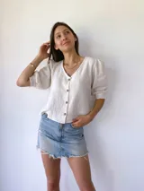 Blusa de muselina color crudo, con mangas tres cuartos abullonadas y botones de madera.