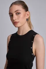 Musculosa marrón de tejido liso, con cuello redondo y tachas metálicas decorativas en los hombros.