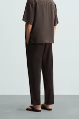 Pantalón de corte relajado (relaxed fit) color verde militar, confeccionado en mezcla de algodón y lino. Presenta cintura elástica ajustable con cordón y bolsillos frontales y traseros de vivo.