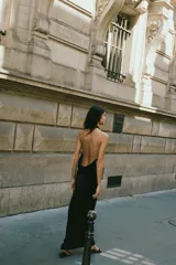 Vestido midi negro de tejido fluido, con cuello halter y escote drapeado en delantero y espalda.