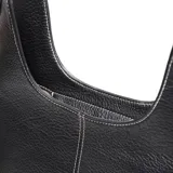 Bolso tipo hobo o media luna de cuero sintético negro texturizado, con costura central vertical en hilo blanco. Incluye asa corta fija y una correa larga desmontable tejida con patrón de espiga en blanco y negro. Posee herrajes metálicos dorados y un logo metálico con la inscripción "XL" en el frente.