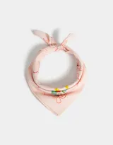 Pañuelo cuadrado de algodón color rosa pálido con estampado de flores y moños rojos.