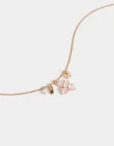 Collar de cadena dorada con dije de flor esmaltada en blanco y rosa, con charms de mariposa, perla y cristal.