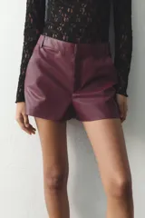 Shorts de tiro alto color borgoña, con bolsillos delanteros y cierre frontal con cremallera y ganchos metálicos.