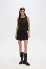 Chaleco negro con escote redondo, sin mangas, corte al cuerpo y cierre frontal con botones. Presenta un bolsillo de ojal en el frente.