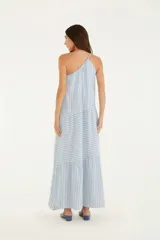 Vestido largo de rayas verticales celestes y blancas, con un solo tirante fino en el hombro izquierdo y corte asimétrico con volantes en la falda.