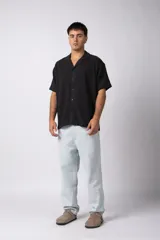 Camisa de manga corta color crudo, confeccionada en lino texturizado. Tiene cuello tipo cubano, cierre frontal con botones y corte recto.