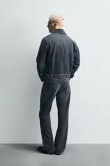 Pantalón de jean de tiro medio, color gris oscuro con efecto lavado, corte ajustado en la parte superior y acampanado desde la rodilla, con cinco bolsillos y cierre frontal con cremallera y botón.