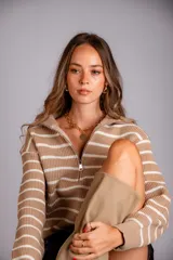 Sweater de punto color beige con rayas horizontales blancas, cuello polo con cierre de cremallera y mangas largas.