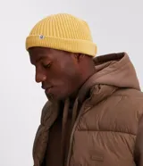 Gorro corto tipo beanie color beige, tejido en lana acrílica con textura acanalada.
