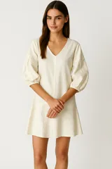 Vestido corto color crema de lino, con escote en V y mangas 3/4 abullonadas.