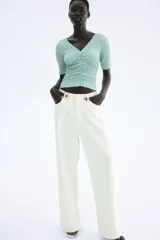 Top color celeste con textura arrugada, escote en V, mangas cortas y frunces en el delantero y los laterales.